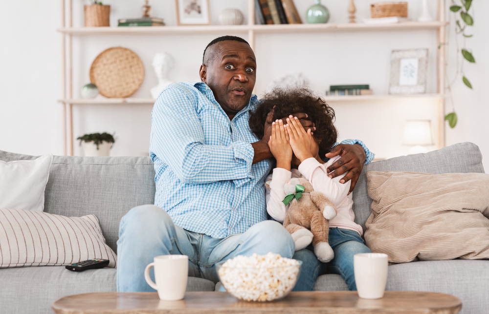 Father and daughter watching scary movie.