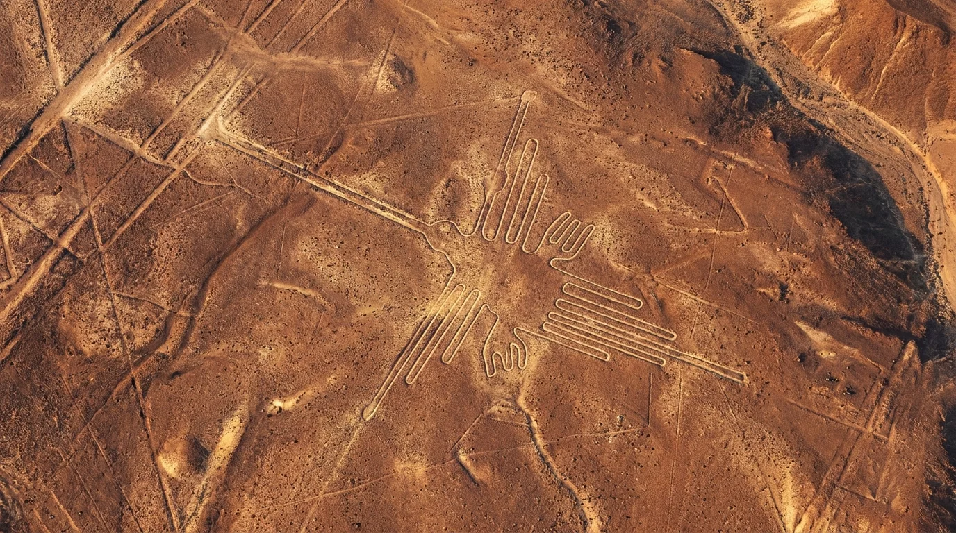 An aerial view of the ancient Hummingbird geoglyph etched into the reddish-brown Peruvian desert soil.